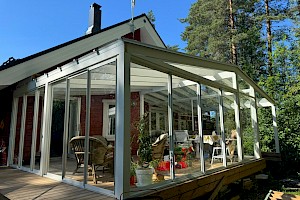 Valkoinen liimapuurunkoinen lasiterassi harjakatolla