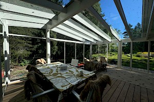 Valkoinen liimapuurunkoinen lasiterassi harjakatolla