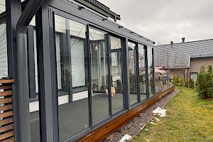 Harmaa liimapuurunkoinen lasiterassi